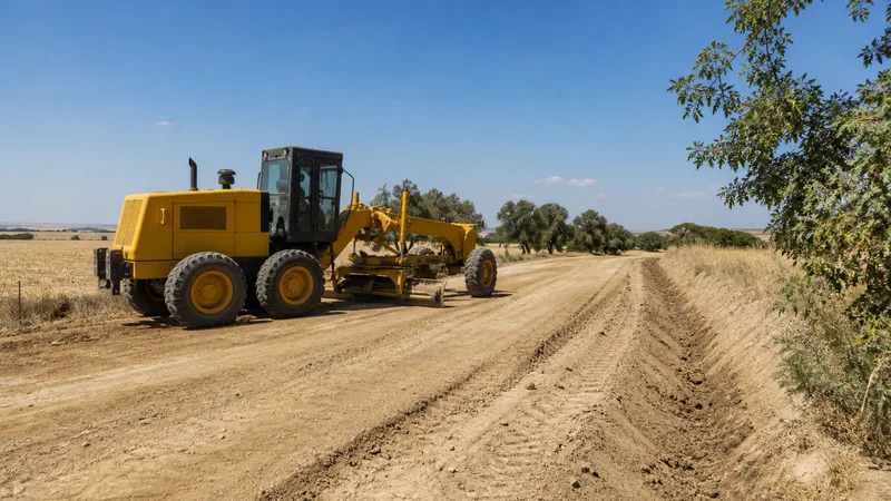 Motoniveladora genérica acondicionando un camino rural de tierra y su cuneta