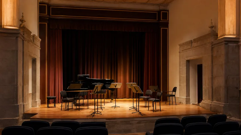 Escenario genérico y vacío de un teatro histórico con piano, atriles y butacas sin público