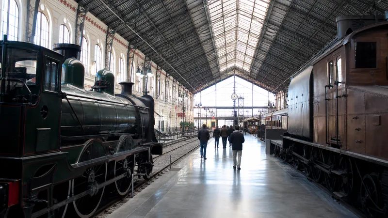 Locomotoras históricas y andenes bajo una gran nave ferroviaria