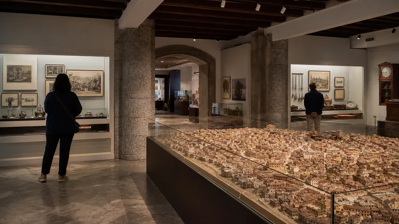 Visitantes contemplan una maqueta urbana y objetos históricos en un museo