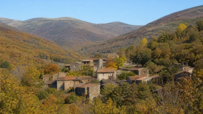 Pequeño pueblo de piedra y tejados oscuros entre montes de la Sierra del Rincón