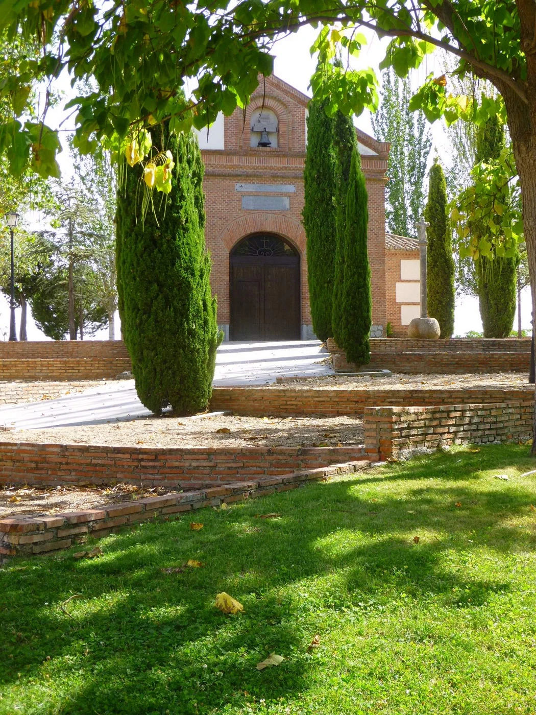 Ermita de San Roque entre cipreses y árboles en Navalcarnero