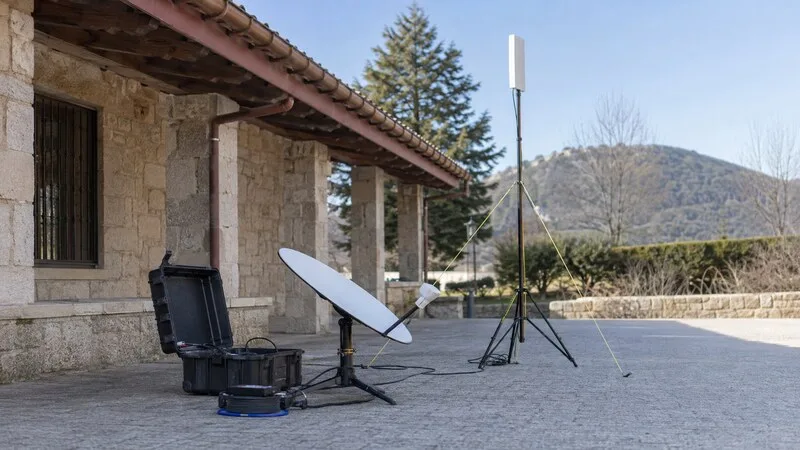 Equipo temporal de telecomunicaciones con antena satelital y mástil móvil en un entorno rural