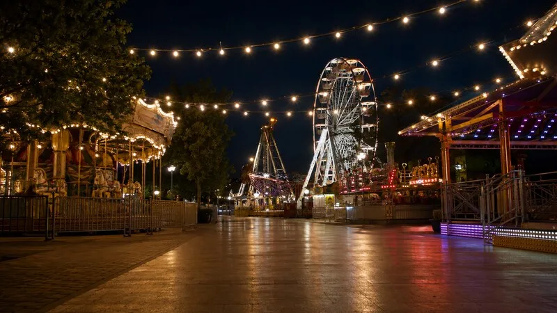 Recinto ferial iluminado de noche con noria y atracciones