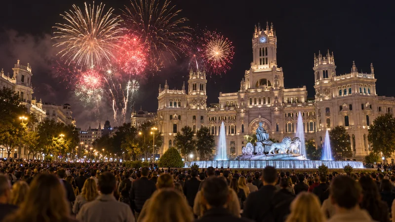 Público ante la fuente y el Palacio de Cibeles mientras estallan fuegos artificiales.